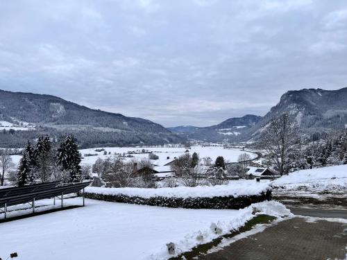 a bench sitting in the snow next to a river at Panoramablick Scheifling in Lind bei Scheifling