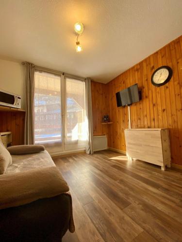1 dormitorio con 1 cama y reloj en la pared en Centre station - LA FOUX D'ALLOS - Charmant T2 en Allos