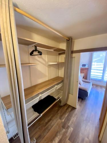 Cette chambre comprend un placard avec des étagères et un canapé. dans l'établissement Centre station - LA FOUX D'ALLOS - Charmant T2, à La Foux