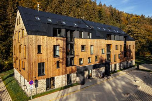 a large brick building with a black roof at Apartmány Mlýn Herlíkovice in Hořejší Vrchlabí