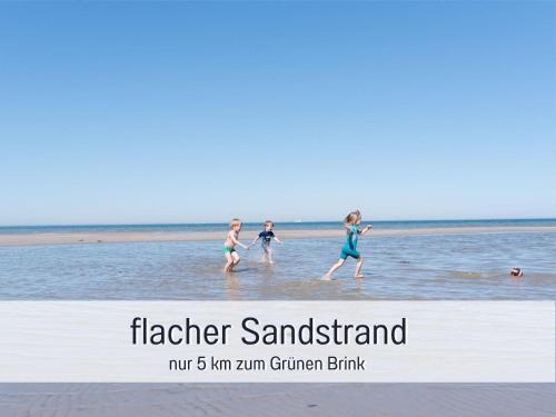 três meninas andando na água na praia em Bio Ferienhof Wichtelweide - Ferienhaus Lichtblick em Fehmarn