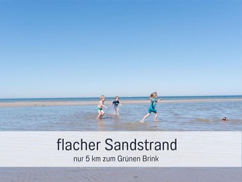 three girls walking in the water on the beach at Bio Ferienhof Wichtelweide - Ferienhaus Lichtblick in Fehmarn