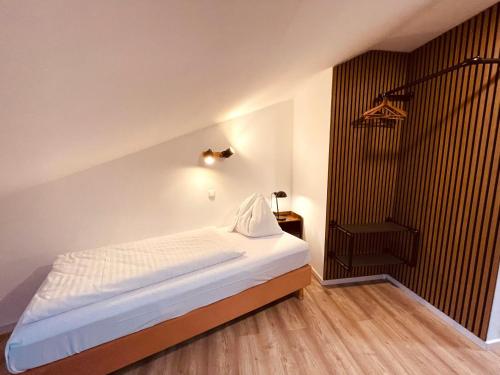 a bedroom with a white bed and a wooden floor at Gästehaus am Stadtpark in Vöcklabruck