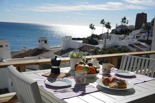 stół z jedzeniem na balkonie z widokiem na ocean w obiekcie La Casa de Colores w mieście Estepona