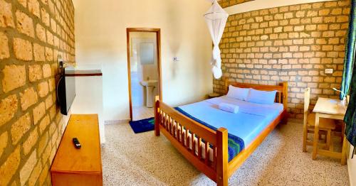 1 dormitorio con cama y pared de ladrillo en Iziba lodge, en Hoima