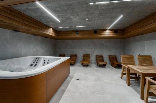 a room with a tub and chairs and tables at Mlýn Herlíkovice in Hořejší Vrchlabí