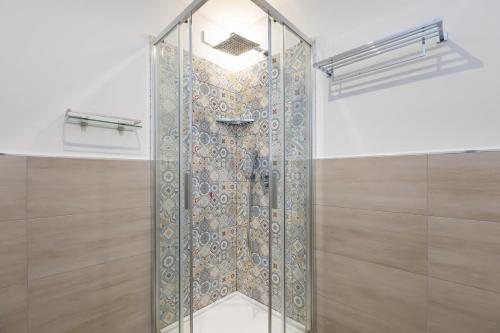 La salle de bains est pourvue d'une douche avec une porte en verre. dans l'établissement MagnoliaApartments - 16 Meravigli Duomo, à Milan