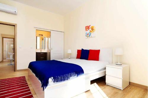 a bedroom with a large white bed with red and blue pillows at Lightoasis Oeiras 6 in Oeiras