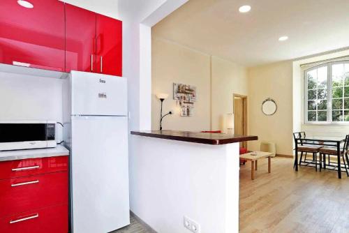 a kitchen with a white refrigerator and red cabinets at Lightoasis Oeiras 6 in Oeiras