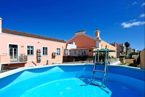 a blue swimming pool with a ladder in front of a house at Lightoasis Oeiras 6 in Oeiras