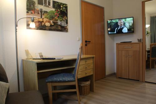 Zimmer mit einem Schreibtisch und einem TV an der Wand in der Unterkunft Gästehaus Niemerg in Warendorf