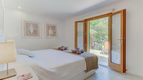 ein weißes Schlafzimmer mit einem Bett und einer Glasschiebetür in der Unterkunft Casa Oliver in El Port