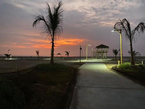 einen Sonnenuntergang am Strand mit Palmen und Bürgersteig in der Unterkunft YAKY'S TOPARA in Jaguay