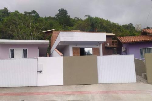 ein weißer Zaun vor einem Haus in der Unterkunft Casa de praia com piscina em Governador Celso Ramos in Governador Celso Ramos