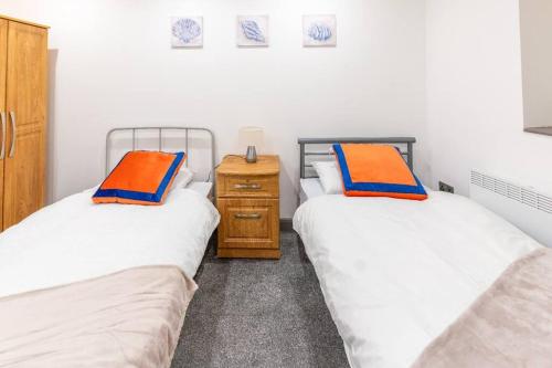 two twin beds in a room with a night stand at Cosy 2 Bedroom Flat in Bradford, on street parking in Bradford