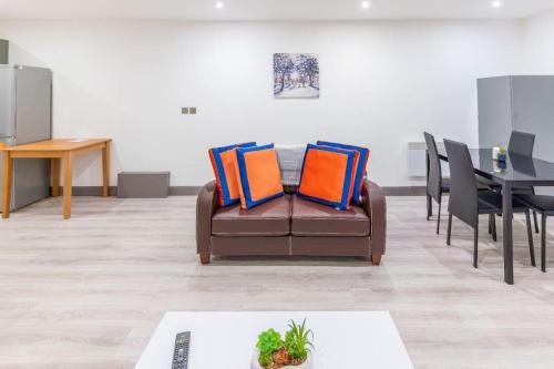 a brown couch with orange and blue pillows in a room at Cosy 2 Bedroom Flat in Bradford, on street parking in Bradford