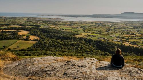 a woman sitting on top of a rock looking out over a valley at Cosy barn conversion in the Mournes in Newry