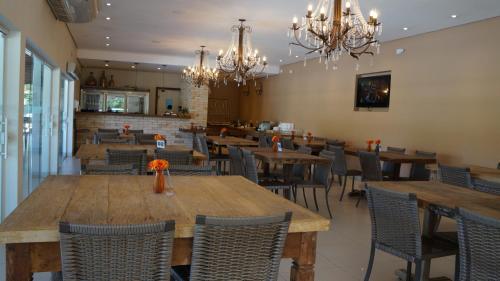 un restaurante con mesas de madera, sillas y lámparas de araña en Hotel Beira Rio, en Piraju