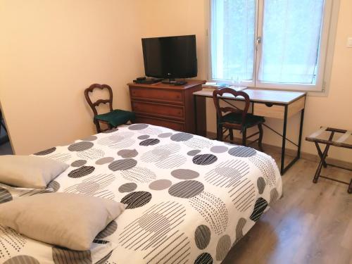 - une chambre avec un lit, un bureau et une télévision dans l'établissement Chambre et table d'hôtes La Meule, à Poligny