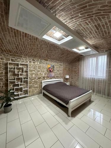 Un dormitorio con una cama y una pared de ladrillo. en 2х кім-й Loft на площі Філармонії by Willox, en Chernivtsi
