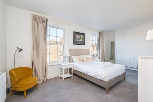 a white bedroom with a bed and a chair at Pass the Keys Luxurious Duplex with Parking in York