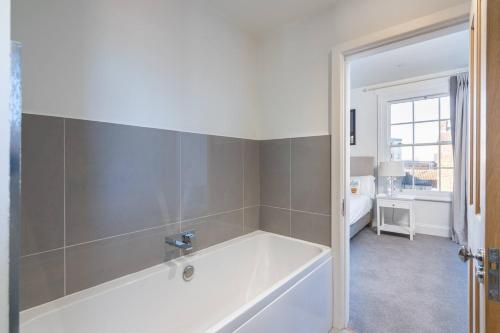a bathroom with a bath tub and a bedroom at Pass the Keys Luxurious Duplex with Parking in York
