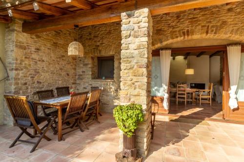 un patio al aire libre con mesa de madera y sillas en Casa Rural Can Ginesta en Sant Feliu de Boada