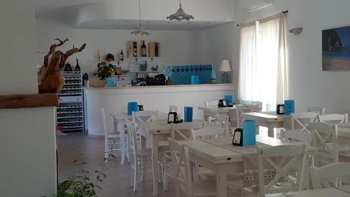 a dining room with white tables and white chairs at Case vacanze NIOLEO - Apartments and Pool in Siniscola