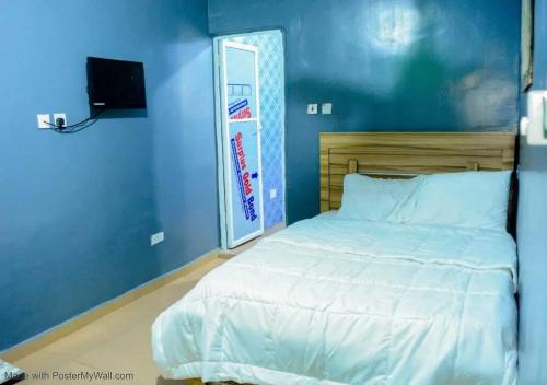 a bedroom with a white bed and a blue wall at Elios Hotels in Ughelli