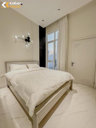 um quarto branco com uma cama grande e uma janela em كرم شاليه em Barka