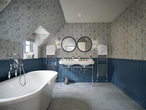 a bathroom with a tub and a sink and mirrors at Townhouse Suites- Abbey Row in Malmesbury