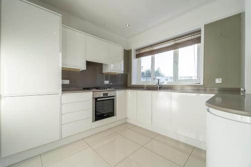 a white kitchen with white cabinets and a window at A Piece of Seaside Serenity on the Sandbanks Peninsula in Sandbanks