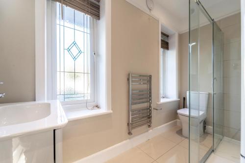 baño con lavabo y aseo y ventana en A Piece of Seaside Serenity on the Sandbanks Peninsula, en Sandbanks