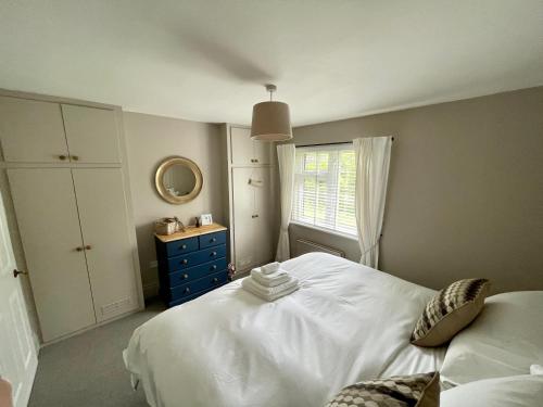 um quarto com uma cama branca e uma cómoda azul em Seaside Spacious Cosy Cottage On The Edge Of The New Forest em Lymington