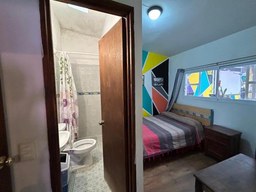a bathroom with a bedroom with a bed and a toilet at Hostel Casa De Yagil in San Cristóbal de Las Casas