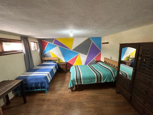 2 camas en una habitación con una pared colorida en Hostel Casa De Yagil, en San Cristóbal de Las Casas