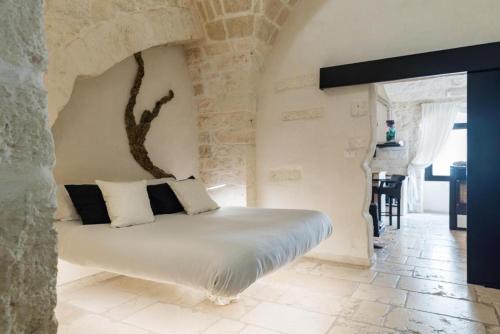 - une chambre avec un lit et un arbre sur le mur dans l'établissement Rifugio del Monsignore, à Ostuni