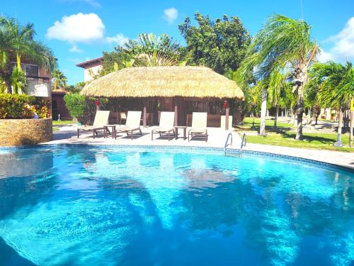 una piscina con sillas y una cabaña de paja en Aruba Eagle beach home en Palm-Eagle Beach