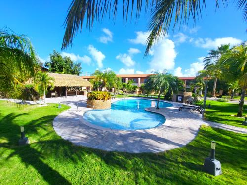 una piscina en un patio con palmeras en Aruba Eagle beach home en Palm-Eagle Beach