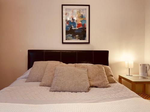a bed with pillows and a picture on the wall at Aston Henry James William Street Close to Reading Town Centre in Reading