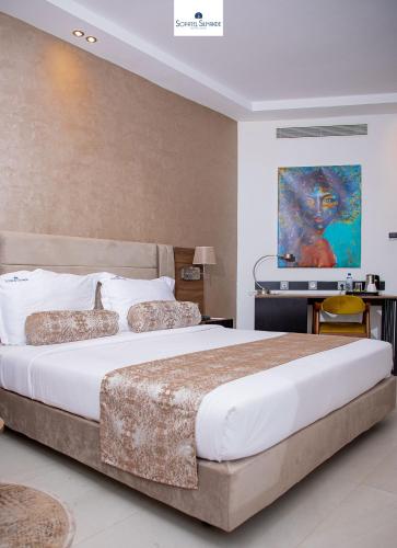 a bedroom with a large bed and a painting on the wall at Sopatel Silmandé in Ouagadougou