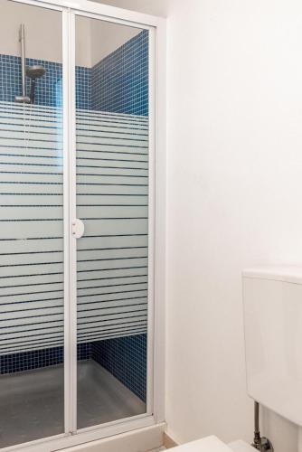 a glass shower door in a bathroom with blue tiles at Boutique Villa Olivia in Agios Pavlos