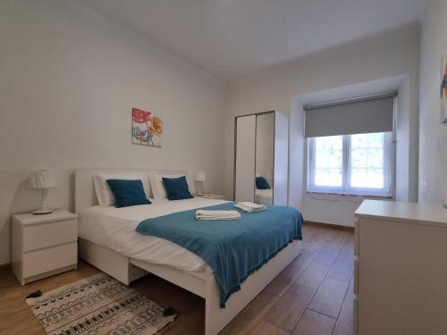 a bedroom with a bed with blue sheets and a window at Lightoasis Oeiras 7 in Oeiras