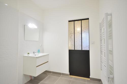ein weißes Badezimmer mit einem Waschbecken und einem Spiegel in der Unterkunft Le Wlérick 5- Hyper centre - Au calme -Wifi in Mont-de-Marsan
