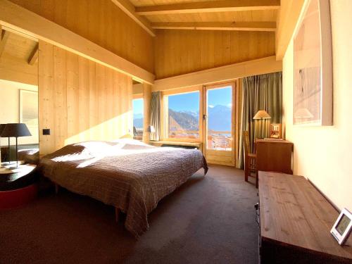 a bedroom with a bed and a large window at B L A C K B I R D V E R B I E R Trés rare et exclusif penthouse de 160 m2 in Verbier