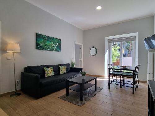 a living room with a black couch and a table at Lightoasis Oeiras 7 in Oeiras