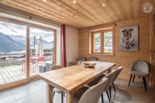 a dining room with a wooden table and a large window at Chalet Alpin Luxe, Jacuzzi, Vue in Champagny-en-Vanoise