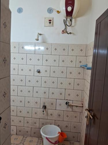 a bathroom with a bucket on a tiled wall at Homely Home stay in Kalpetta