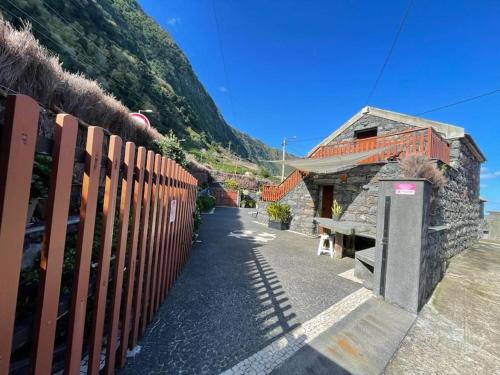 a fence next to a building next to a mountain at Cozy chalet with ocean view in Seixal