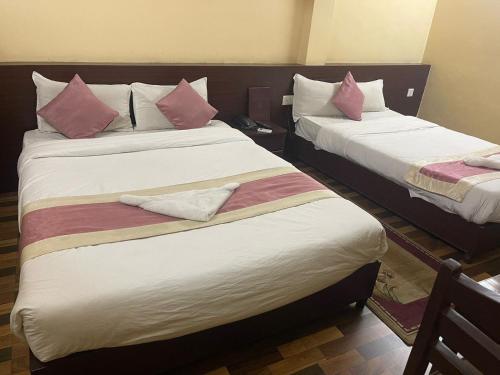 2 łóżka w pokoju hotelowym z różowymi poduszkami w obiekcie Rameshworam Hotel w Katmandu